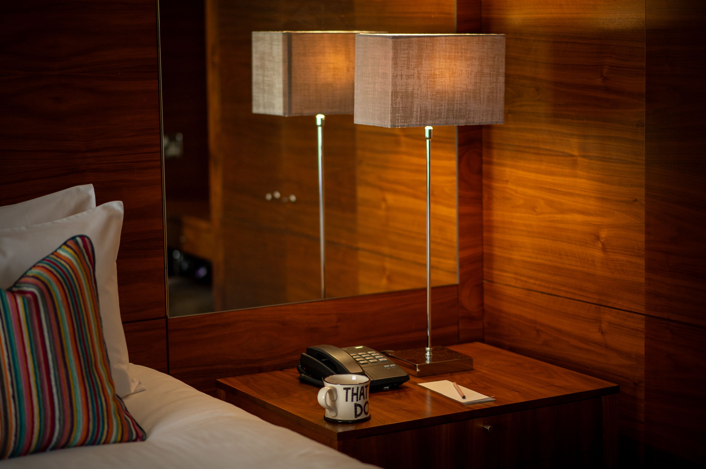 bedside table with lamp, phone and cup of tea