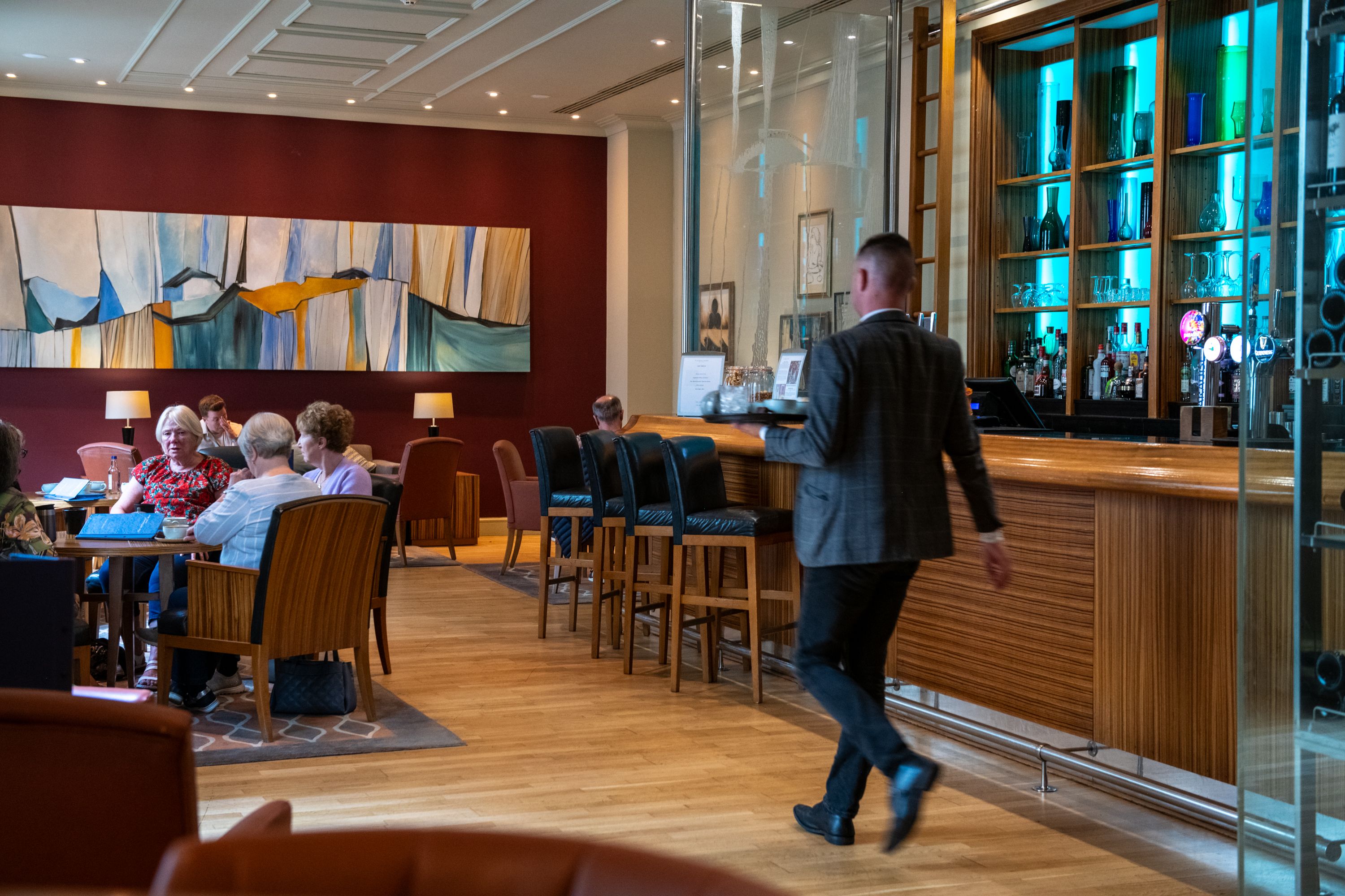 waiter walking through a bar with people sitting in it