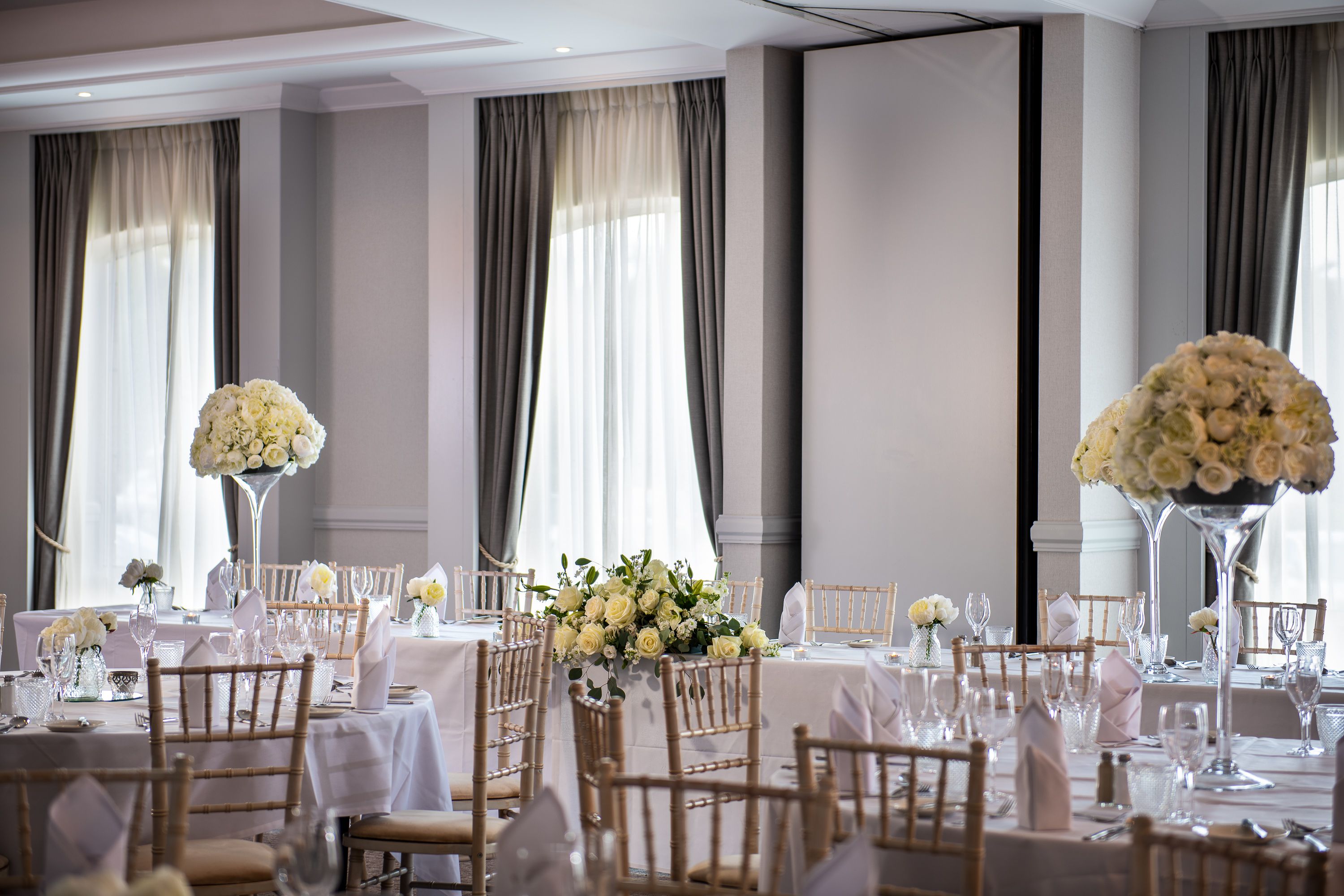 function room set up for wedding with large round tables and flower centre pieces